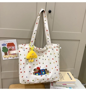 Close-up of white canvas tote bag with colorful polka dots and plush dog patch detail