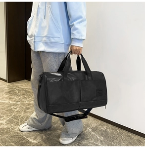 Detail of black matte leather travel bag with durable handles and wide shoulder strap