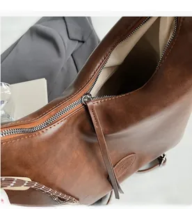 Dettaglio della cerniera argentata e del logo sulla borsa tote in pelle vintage