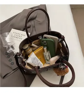 Macro view showing spacious interior of dark brown leather tote bag with diverse daily items