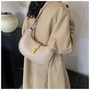 Detail view of beige lychee leather shoulder bag with gold metal buckle on a model