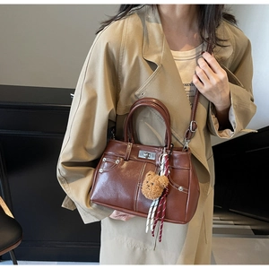 Détail du sac à main vintage marron avec coutures denim et breloque ours en peluche