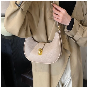 Detail of lychee textured leather crescent bag with elegant gold metal buckle and beige finish