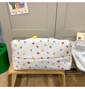 Detail view of the colorful polka dot pattern on a white canvas dog tote bag