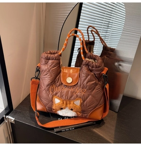 Detail einer braunen Stepp-Tote Bag mit Katzen-Plüsch-Patch und orangen Griffen