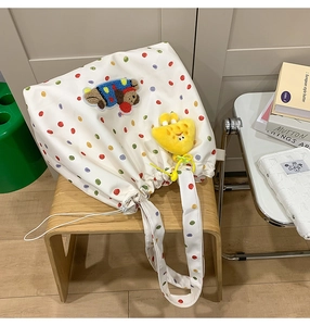 Detailed embroidery of plush bear and yellow sun on white polka dot canvas tote bag