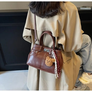 Détail d'un sac à main vintage marron avec bandoulière réglable et breloque ourson