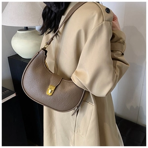 Close-up of brown litchi pattern leather half-moon bag with elegant gold metal clasp
