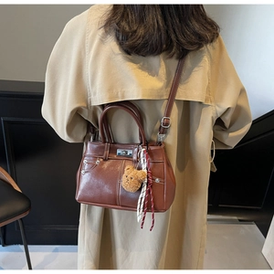 Detail of vintage brown leather handbag featuring white stitching and metal twist lock