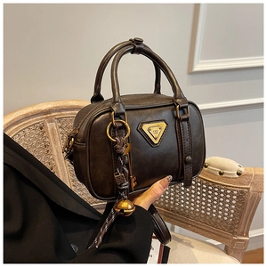 Nahaufnahme der schokobraunen Boston-Tasche mit Metallplakette und Vintage-Anhängern