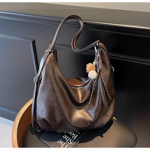 Dettaglio della borsa hobo in pelle marrone scuro con tracolla regolabile e logo goffrato