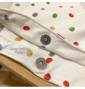 Detail view of the magnetic snap closure on a polka dot canvas tote bag with metal hardware