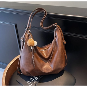 Dettaglio borsa tote vintage marrone scuro con tracolla regolabile e ciondolo a orso