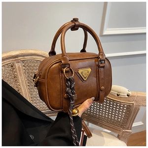 Details der karamellbraunen Vintage-Handtasche mit Metalllogo und Glockenanhänger