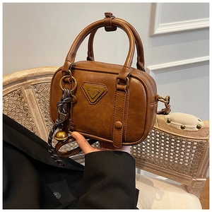 Nahaufnahme der braunen Vintage PU-Leder Tasche mit Metall-Logo und Anhänger-Detail