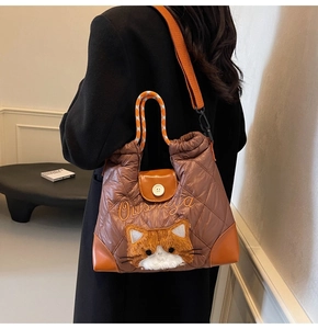 Detail der gesteppten Nylon-Tragetasche mit süßer Katzenstickerei und orangen Lederakzenten