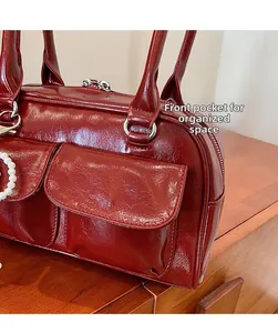 Détail du sac Boston rouge brillant avec poches avant et pendentif en perles