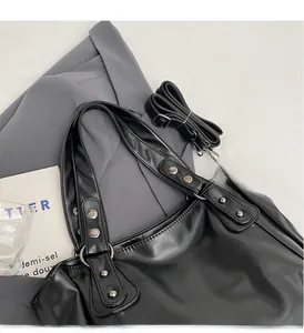 Détail du sac cabas noir mat avec rivets argentés et bandoulière réglable