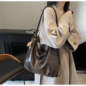 Dettaglio di una grande borsa tote plissettata caffè scuro indossata a tracolla per pendolari