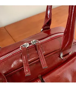 Détail d'un sac en cuir bordeaux brillant avec double fermeture éclair argentée