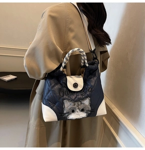 Detail der blauen Stepptasche mit Plüschkatzen-Dekor und kariertem breitem Schultergurt