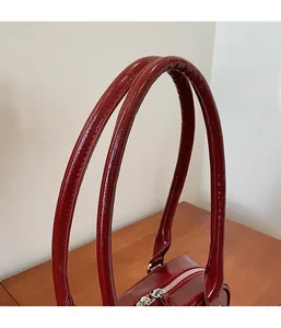 Détail du sac Boston en cuir verni rouge vin avec fermeture éclair en métal argenté