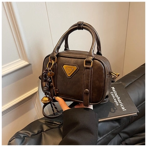 Detail of dark brown vintage mini Boston bag with gold triangle plaque and charms
