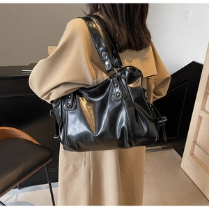Détail du grand sac cabas noir en cuir avec rivets et texture plissée élégante