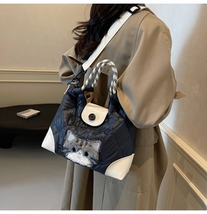 Detail der marineblauen Stepp-Tasche mit Katzenmotiv und weißen Lederbesätzen am Model