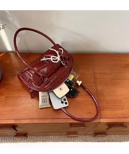 Vue de dessus du sac Boston en cuir verni bordeaux montrant l'intérieur spacieux et objets