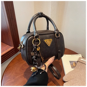 Detail of dark brown vintage leather handbag with metal logo and retro charms decoration