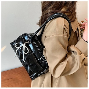 Détail du sac à bandoulière noir brillant avec poches et breloque nœud en perles