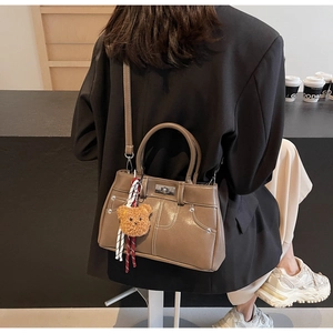 Detail of vintage coffee brown shoulder bag with contrast stitching and bear charm