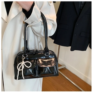 Détail du sac Boston en cuir verni noir avec pendentif perle et deux poches sur le devant
