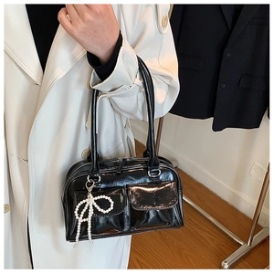 Vue détaillée du sac Boston en cuir verni noir avec pendentif nœud en perles et poches doubles