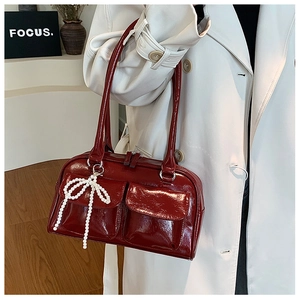 Détail du sac Boston bordeaux en cuir verni avec nœud en perle et poches avant