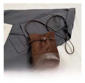 Close-up of brown frosted leather bucket bag with metallic buckle and suede texture