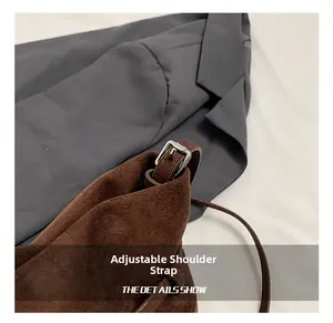 Detail of adjustable slender shoulder strap with silver buckle on dark brown suede bucket bag