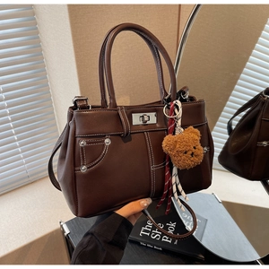 Detail of dark brown faux leather handbag with white stitching and silver metal turn lock