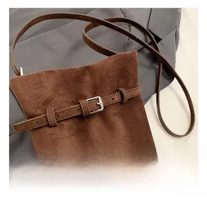 Detail of brown suede bucket bag featuring refined silver buckle and belt texture