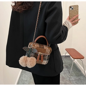 Détail du mini sac à carreaux en tweed avec poignée en cuir et pendentif cerise