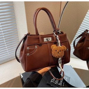 Detail of vintage brown leather handbag featuring contrast white stitching and bear charm