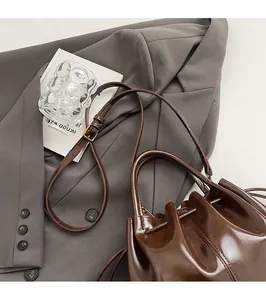 Détail d'un sac seau brillant marron foncé avec des finitions dorées chic