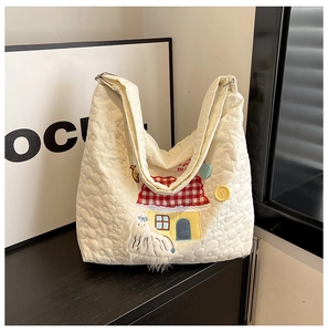 Close-up of quilted nylon tote with floral stitching, 3D lamb doll, and red house patch