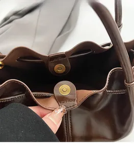 Détail du sac seau en cuir marron foncé avec fermoir magnétique et boucles en laiton