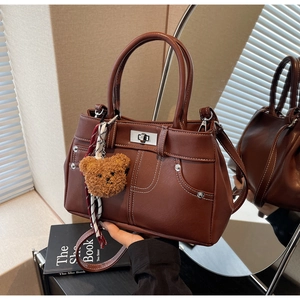 Brown faux leather handbag featuring white contrast stitching and silver twist lock detail