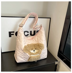 Detail of pink heart-quilted nylon hobo bag featuring a cute plush teddy bear patch