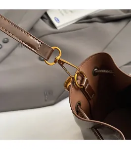 Gros plan détaillé du fermoir doré mat et du cuir marron texturé d'un sac seau