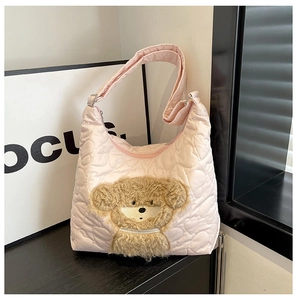 Detailed view of pink quilted nylon shoulder bag featuring heart stitching and a teddy bear patch