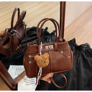 Detail of vintage brown tote with contrast stitching, silver lock and bear charm